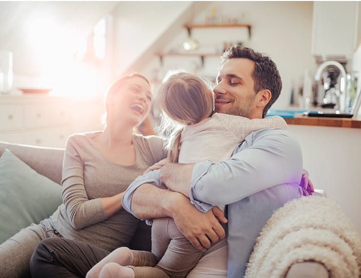 Parents sitting on couch hugging child