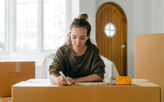 Lady writing notes on home-moving cardboard box